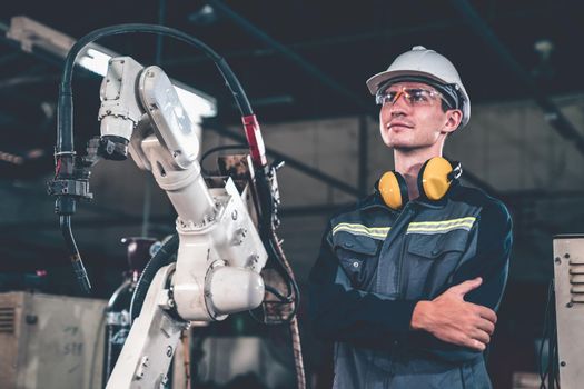 Young factory worker working with adept robotic arm in a workshop . Industry robot programming software for automated manufacturing technology .