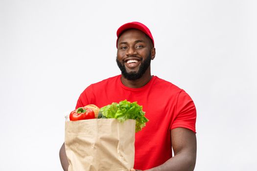 Delivery Concept - Handsome African American delivery man carrying package grocery food and drink from store. Isolated on Grey studio Background. Copy Space.