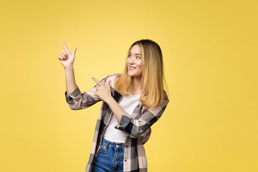 Smiling woman pointing finger side. Isolated portrait on yellow