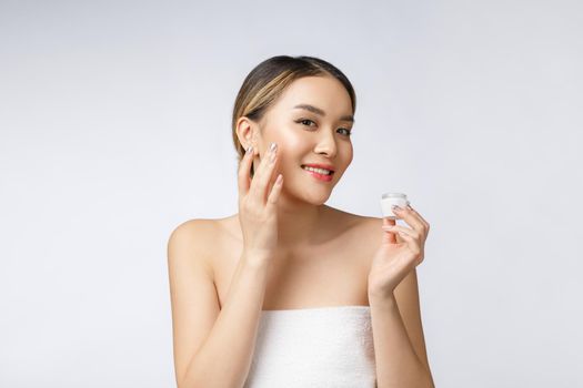 Asian woman applying cosmetic cream on skin on isolated white background.