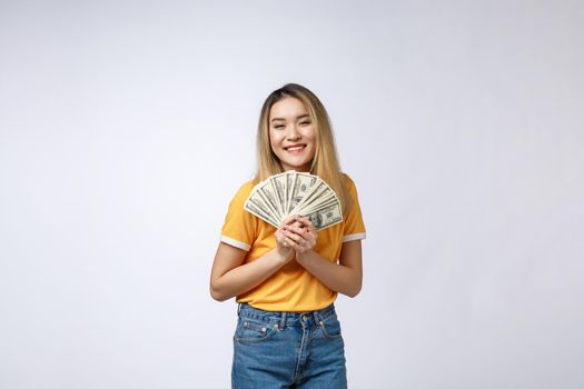 Asian woman holding cash notes isolated in white background. Young asian woman in white t-shirt in winning surprise, holding dollar note. Young rich hipster concept