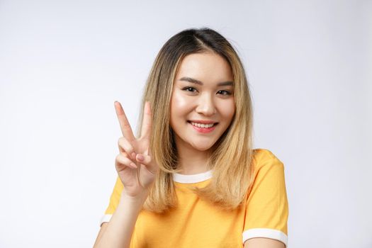 Happy young asian woman showing two fingers or victory gesture with blank copyspace area for text,Portrait of beautiful Asian woman