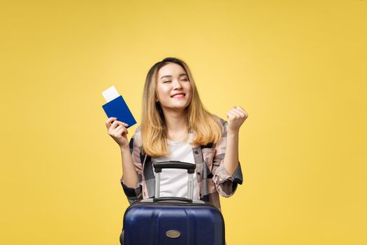 Woman travel. Young beautiful asian woman traveler holding passport ,suitcase and air ticket standing over yellow