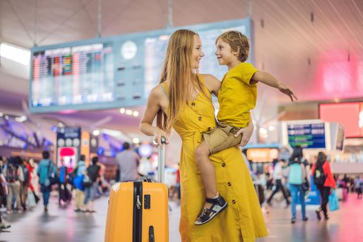 Family at airport before flight. Mother and son waiting to board at departure gate of modern international terminal. Traveling and flying with children. Mom with kid boarding airplane. yellow family look.