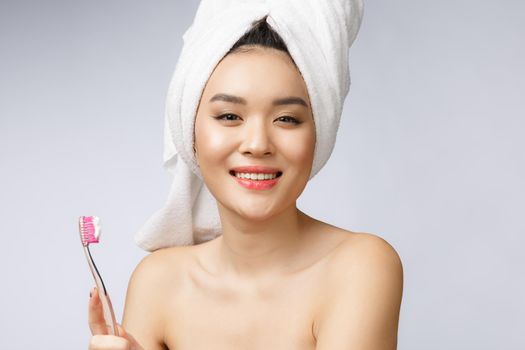 Beautiful young woman on white isolated background holds a toothbrush, Asian.