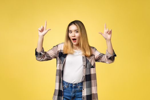 Smiling woman pointing finger side. Isolated portrait on yellow