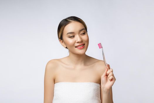 Beautiful young woman on white isolated background holds a toothbrush, Asian.