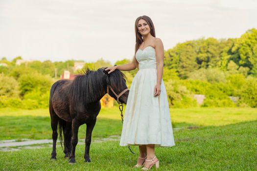 girl next to a pony on the lawn