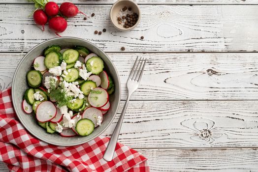 Bowl of healthy vegetarian salad with radish cucumber and fennel. top view on wooden background with copy space, summer food