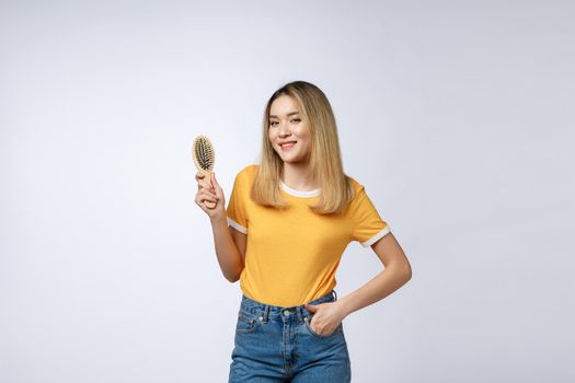 young beautiful woman combing her hair isolated over grey background