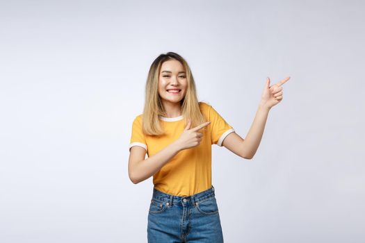 Beautiful young Asian woman pointing her finger up with cheerful expression, on white background