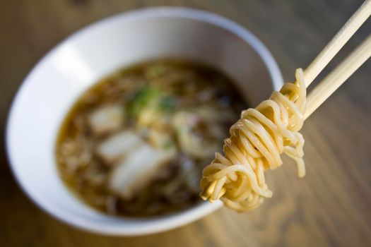 Ramen noodles bowl and some on chopsticks