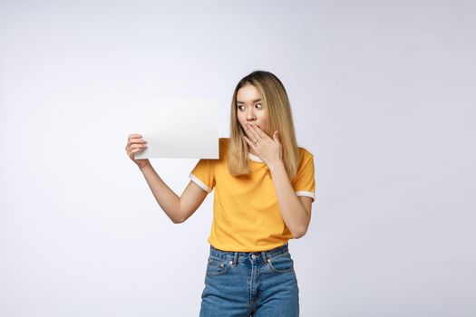 Banner sign woman peeking over edge of blank empty paper billboard with copy space for text. Beautiful Asian Caucasian woman looking surprised and scared - funny. Isolated on white background.