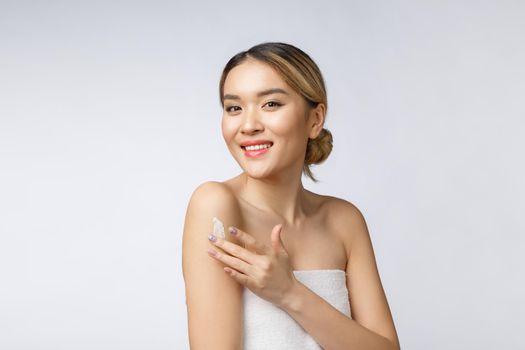 Asian woman applying cosmetic cream on skin on isolated white background.