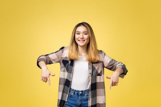 Smiling woman pointing finger side. Isolated portrait on yellow