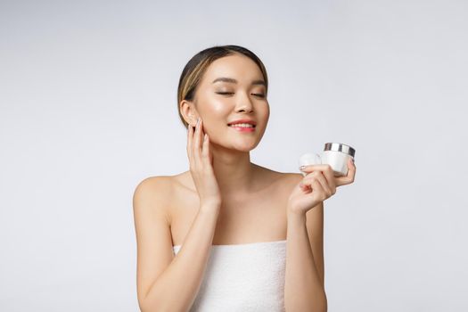 Asian woman applying cosmetic cream on skin on isolated white background.