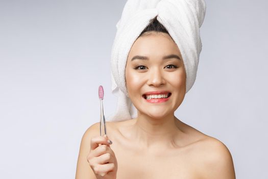 Beautiful young woman on white isolated background holds a toothbrush, Asian.