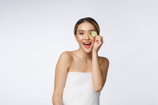 Young asian woman with cucumber slice in her hands isolated on white background