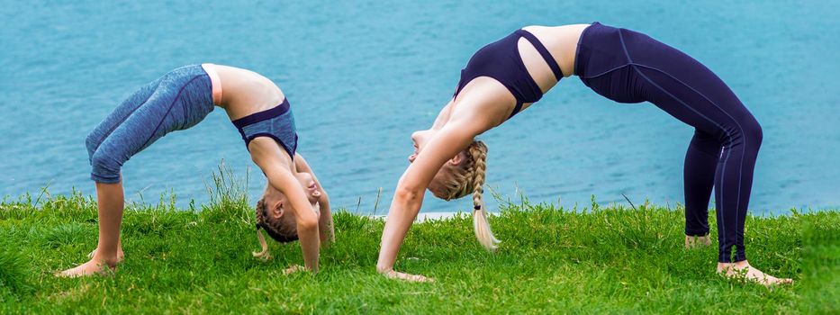 Mother and daughter doing exercise at the shore outdoors. Healthy lifestyle.