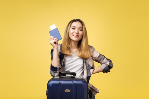 Woman travel. Young beautiful asian woman traveler holding passport ,suitcase and air ticket standing over yellow