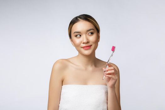 Beautiful young woman on white isolated background holds a toothbrush, Asian.