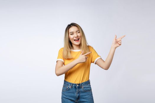 Beautiful young Asian woman pointing her finger up with cheerful expression, on white background