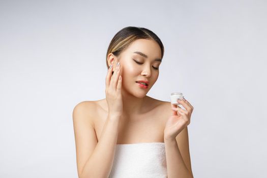 Asian woman applying cosmetic cream on skin on isolated white background.