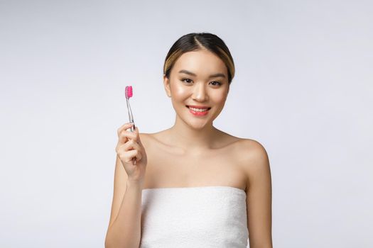 Beautiful young woman on white isolated background holds a toothbrush, Asian.