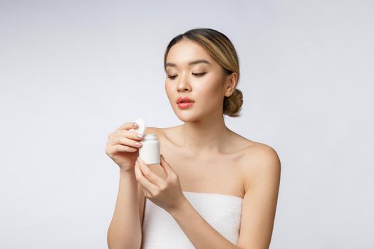 Healthy happy asian woman with pills in hand isolate over white background