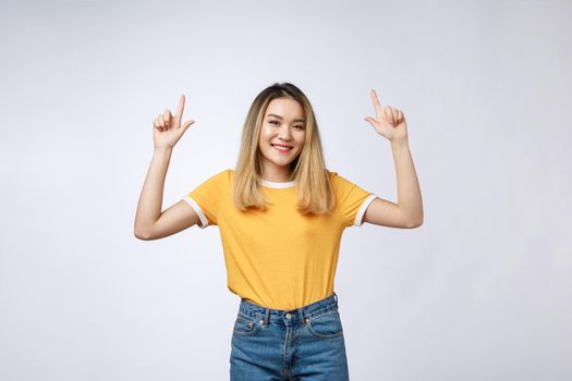 Beautiful young Asian woman pointing her finger up with cheerful expression, on white background