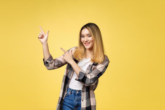 Smiling woman pointing finger side. Isolated portrait on yellow