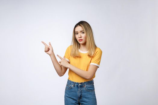 Young Asian woman looking angry and sad while pointing finger at camera isolated against white background