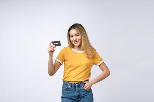 Asian content woman holding fan of money dollar banknotes and credit card and looking on copyspace isolated over gray background