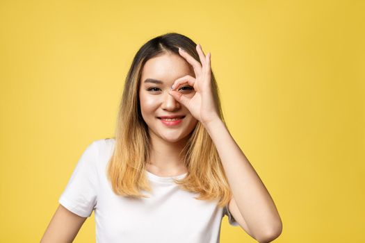 Asian young woman with ok sign gesture isolate over yellow background