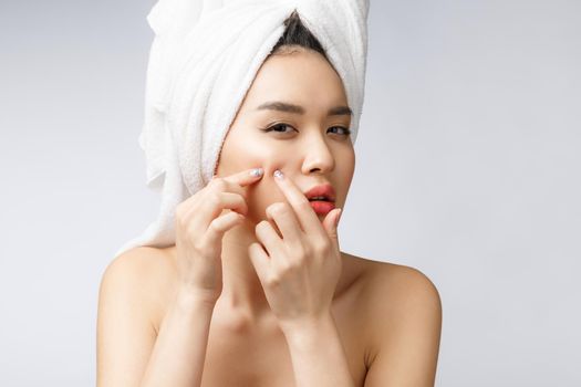 Asian woman looking at pimple on face. Young Woman try to remove her pimple. Woman skin care concept. Isolated on white background.