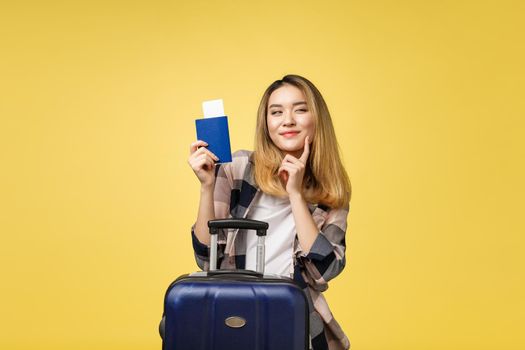 Woman travel. Young beautiful asian woman traveler holding passport ,suitcase and air ticket standing over yellow