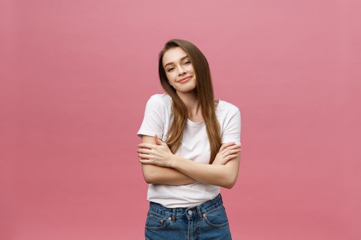 Portrait of a happy woman standing with arms folded isolated on a pink background.