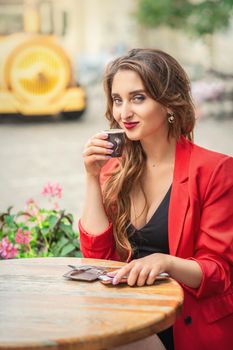 Portrait of beautiful girl having coffee at the table at cafe outdoors.