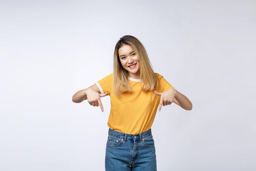 Beautiful young Asian woman point down to blank space on grey background