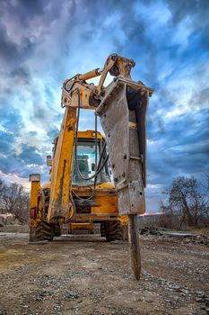 Excavator with hydraulic breaker hammer for the destruction of concrete and hard rock at the construction site or quarry. Demolition equipment