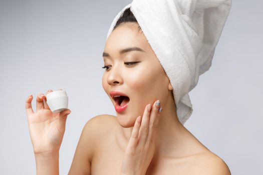 health and beauty concept - Attractive asian woman applying cream on her skin, isolated on white