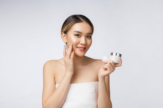 Asian woman applying cosmetic cream on skin on isolated white background.