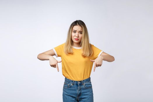 Young Asian woman looking angry and sad while pointing finger at camera isolated against white background