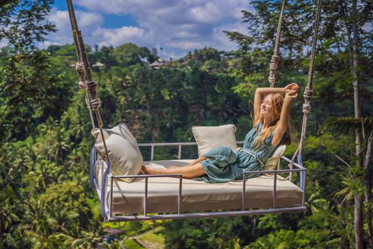Young woman swinging in the jungle rainforest of Bali island, Indonesia. Swing in the tropics. Swings - trend of Bali.