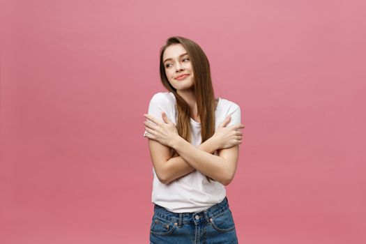 Portrait of a happy woman standing with arms folded isolated on a pink background.