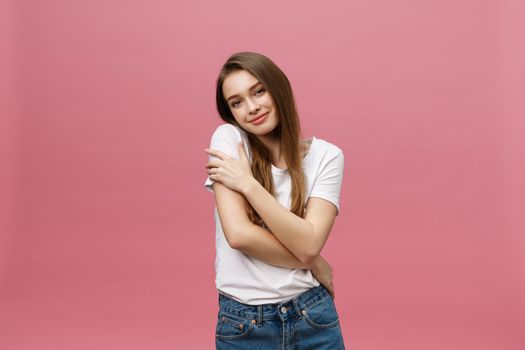Portrait of a happy woman standing with arms folded isolated on a pink background.