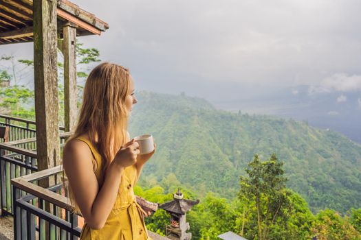 Young woman drinks coffee in a cafe in the mountains.