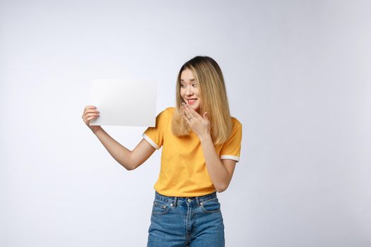 Banner sign woman peeking over edge of blank empty paper billboard with copy space for text. Beautiful Asian Caucasian woman looking surprised and scared - funny. Isolated on white background.