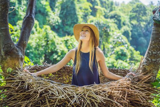 Bali trend, straw nests everywhere. Young tourist enjoying her travel around Bali island, Indonesia. Making a stop on a beautiful hill. Photo in a straw nest, natural environment. Lifestyle.