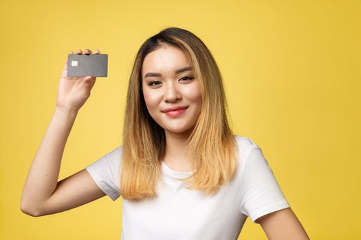 Young smiling beautiful Asian woman presenting credit card in hand showing trust and confidence for making payment